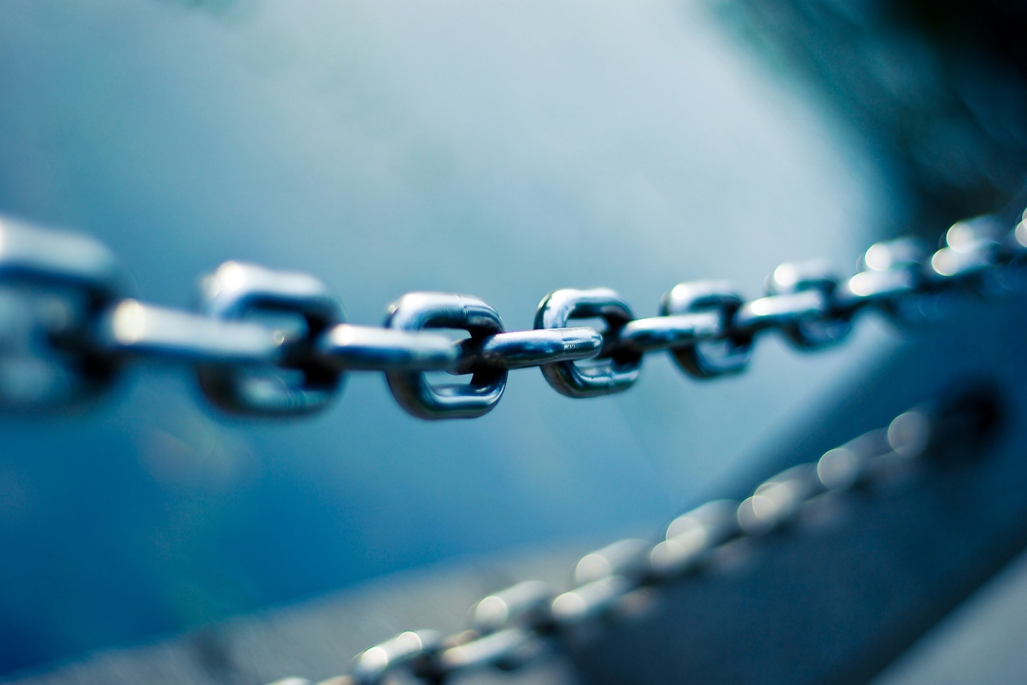 A stainless steel chain in tilt-shift focus, one link sharp among many
