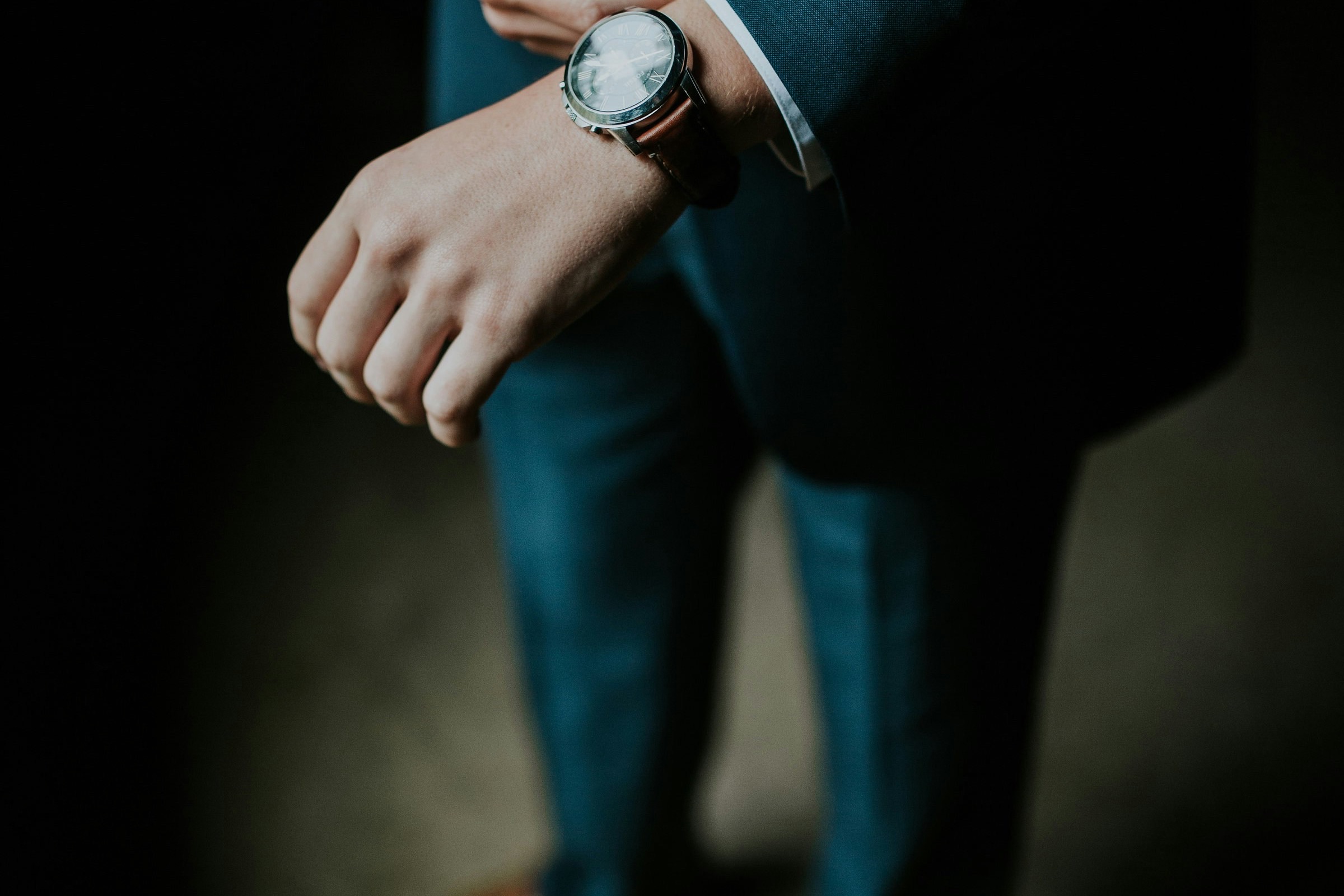 Man adjusting his watch cuff in a tailored suit