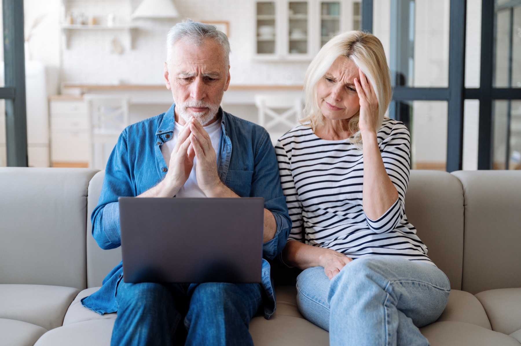 An older couple looking at a laptop together, both with concerned expressions