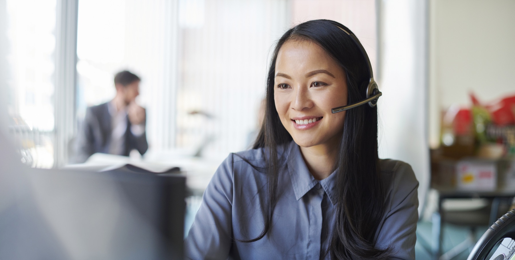 A customer service representative wearing a headset, smiling while working