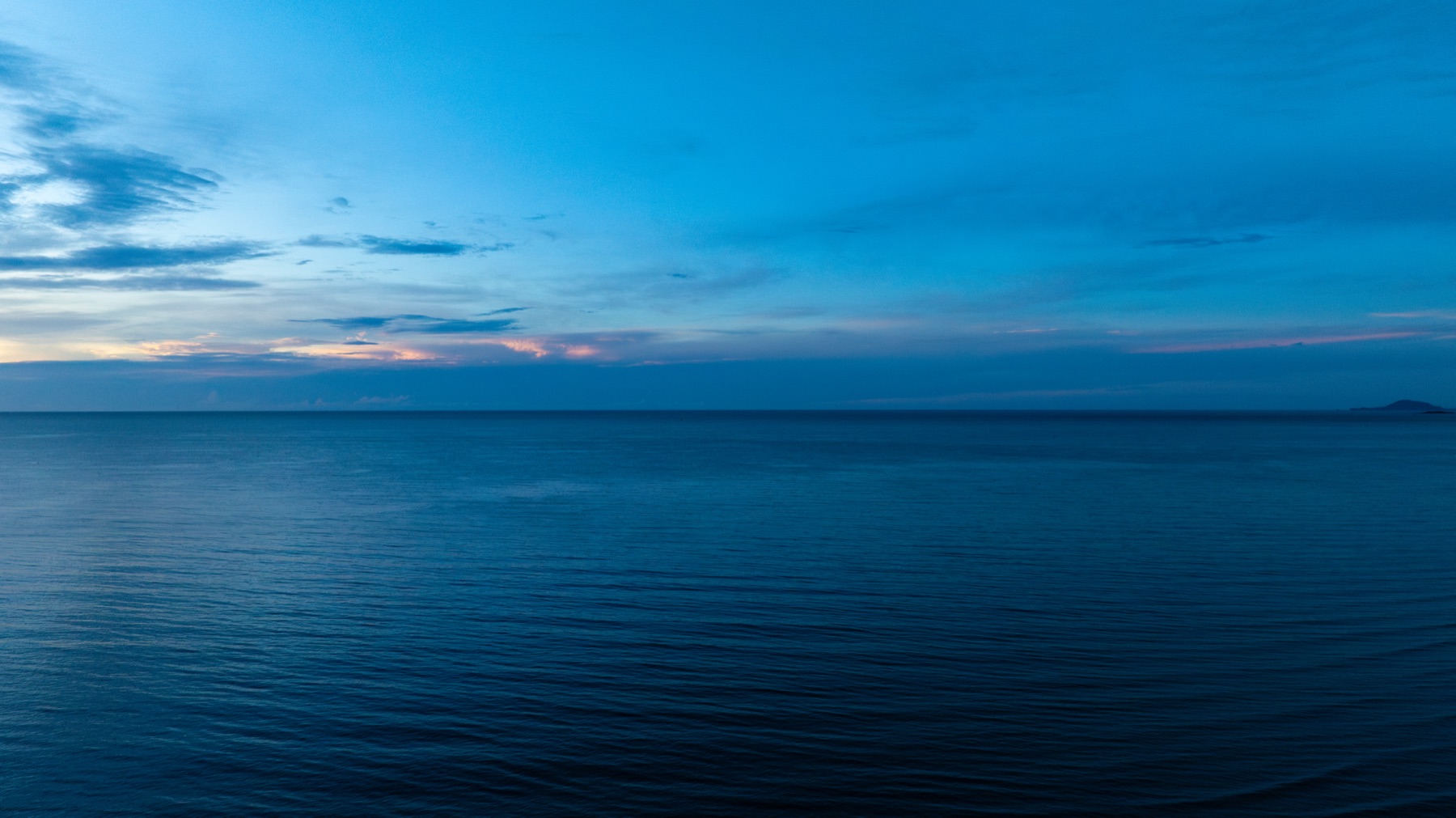 Ocean horizon at dusk, calm water meeting a blue sky